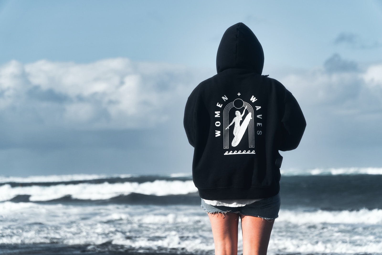 person in black hoodie standing on seashore during daytime